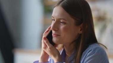 Evde akıllı telefondan konuşan gülümseyen bir bayan. Modern bir dairede oturan mutlu ve çekici bir kadının portresi. Pozitif kız arkadaş cep telefonu iletişiminin keyfini çıkarıyor.