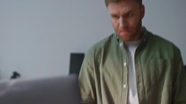 Mutfakta sebze pişirmeye odaklanmış bir adam mutfak videosunu yakından izliyor. Ciddi bir adam internette dizüstü bilgisayara benzeyen taze organik malzemeler hazırlıyor. Genç erkek salata için kırmızı biber dilimliyor..