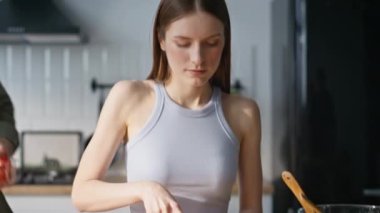 Ev hanımı mutfak tezgahında taze sebze doğruyor. Gülümseyen koca gözlerini kapatıyor karısı evde sağlıklı bir yemek hazırlıyor. Mutlu evli çift yemek hazırlarken birbirlerine sarılıyorlar.