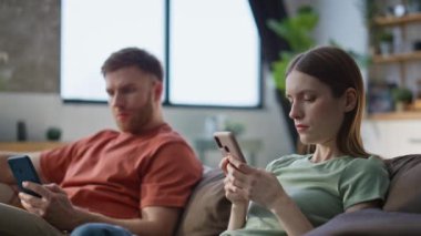 Evli çift evdeki kanepeye yakın oturan cep telefonlarına odaklanmış. Ciddi bir eş, oturma odasında birbirini görmezden gelen akıllı telefonlara konsantre oluyor. Evde cep telefonu mesajlaşmasına katılan eşler
