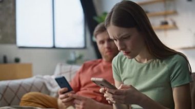 Endişeli eş, kocasına akıllı telefon mesajı gösteriyor. Kanepe oturma odasında yan yana oturuyorlar. Endişeli evli çift cep telefonuyla evde kötü haberler okuyor. Somurtkan kız arkadaş mesaj alıyor.