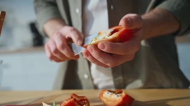 Erkek elleri mutfak tezgahında biber doğruyor. Bilinmeyen adam, ev mutfağında sağlıklı diyet salatası için taze malzemeler hazırlıyor. Genç erkek vejetaryen yemeği pişiriyor. Doğal organik besin