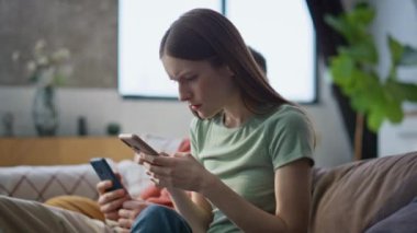 Sorunlu aile, oturma odasındaki cep telefonundan yakın çekimde mesaj alıyor. Endişeli eş, ciddi kocaya akıllı telefondan banka kredisi bildirimi gösteriyor. Endişeli evli çift cep telefonlarını evde arıyor.