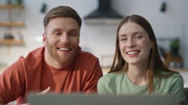 Karı koca video toplantısında konuşuyor. Ev kanepede dizüstü bilgisayar kamerasına bakıyor. Gülümseyen romantik çift uzak arkadaşlara çevrimiçi arıyor. Neşeli genç eşler kanepede uzaktan haberleşmenin tadını çıkarırlar..