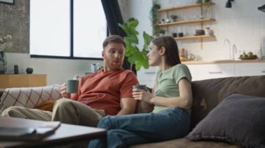 Rahat bir çift, apartman kanepede kahve içerek konuşuyor. Kaygısız eşler ellerinde fincanlarla evdeki kanepede hoş sohbetler yapıyorlar. Hoş bir çift, keyifli bir sabah geçiriyor. Oturma odasında dinleniyorlar..