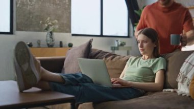 Dizüstü bilgisayarda çalışan bir kadın koltukta rahat bir şekilde yatıyor. İlgilenen koca meşgul eş serbest çalışana kahve fincanı getiriyor. Mutlu eşler oturma odasında sıcak içeceğin tadını çıkarıyorlar. İlişki kavramı.
