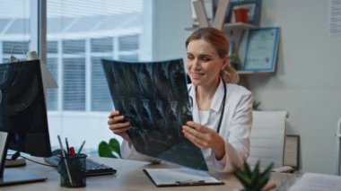 Revirde röntgen çekerken gülümseyen kadın. Yakın çekim doktoru modern hastanede tedavi sonuçlarının tadını çıkarıyor. Hasta radyolojisini klinikte inceleyen neşeli bir travmatolog.. 