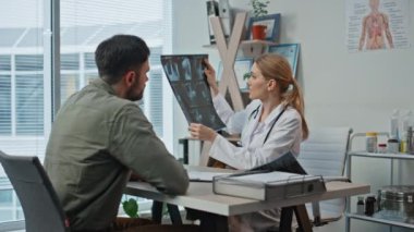 Klinikte röntgen çektiren bir doktora danışıyorum. Muayene sırasında gülümseyen tıbbi uzman teşhisi açıkladı. Konuşan pratisyen adam tarama sonuçları modern sağlık hizmetleri ofisinde..