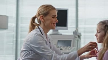 Pediyatrist klinikteki vücut ısısını kontrol ediyor. Modern sağlık merkezinde aile doktoru çocuk babasıyla konuşuyor. Gülümseyen doktor pratisyen kız. Çocuk terapistinde mutlu bir baba.