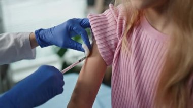 Eller, güzel kıza bağışıklık aşısı yapıyor. Klinikte çocuk doktoru ziyaret eden güzel bir çocuk. Bilinmeyen sağlık görevlisi hemşire çocuk bakım tesisinde şırıngayla aşı yapıyor..