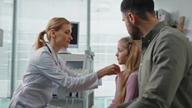 Gülümseyen doktor muayene odasında sıcaklık ölçüyor. Babası tatlı kızıyla kliniğe gitmiş. Profesyonel kadın pediyatrist, ailesine danışmanlık yapıyor. Çocuk bakımı konsepti.