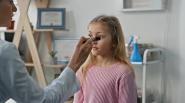 Çocuk doktoru check-up sırasında göz reflekslerini test ediyor. Yakından sarışın güzel bir kız klinikte sağlık görevlisini ziyaret ediyor. Nörolog çocuk sağlığı danışmanlığını muayene odasında kontrol ediyor..