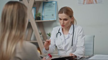 Doktor klinikte reçeteyi açıklıyor. Kapalı çekim gülümseyen kadın randevusu sırasında bilinmeyen bir hastaya danışarak notlar yazıyor. Arkadaş canlısı sağlık pratisyeni danışma tedavisi diyet takviyesi