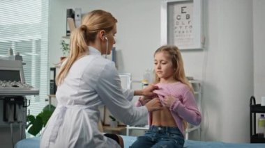 Muayene odasında akciğerleri dinleyen bir çocuk doktoru. Özel klinikteki pratisyen hekimi ziyaret eden sevimli çocuk solunumu. Beyaz önlüklü profesyonel sağlık çalışanı steteskop kullanarak hastayı muayene ediyor
