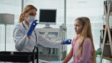 Klinik doktoru küçük kız için aşı hazırlıyor. Tıp hemşiresi muayene odasında şırınga kullanıyor. Tatlı gülümseyen çocuk ziyaretçi pratisyen doktor. Çocuk bakımı bağışıklık kavramı.