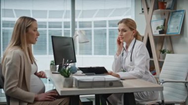 Hasta randevu sırasında tıbbi belgeleri imzalıyor. Modern klinikte jinekoloğu ziyaret eden bir kadının sigorta belgelerini doldurmasını bekliyorum. Steteskoplu mutlu doktor hamilelikle ilgili danışmanlık yapıyor..