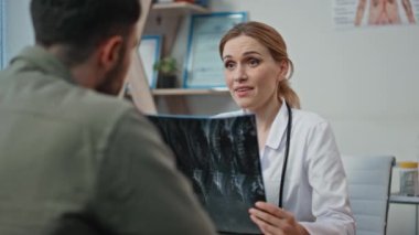 Röntgen analizi yapan hastalarla iletişim kuran bir sağlık görevlisi. Yakın plan kadın doktor, başarılı terapi görüşmeleri yapıyor ve erkeklerle tokalaşıyor. Randevu sırasında radyograf taramasında iyi çalışmalar.