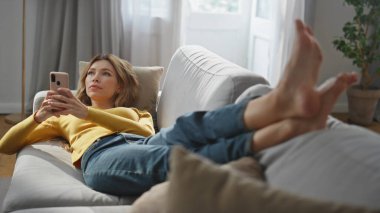 Hayalperest kız rahat koltukta cep telefonunu dinlendiriyor. Oturma odasında elinde akıllı telefon olan ciddi, ürpertici bir kadın. Rahat bayan yumuşak kanepeye uzanmış bakıyor. Teknolojiler ve insanlar