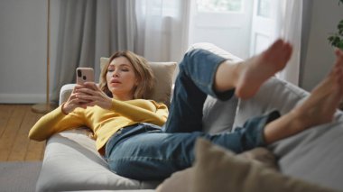 Model olarak rahat koltukta cep telefonu ekranını izliyorum. Oturma odasının içinde elinde akıllı telefon tutan sakin, sakin bir kadın. Haftasonunu yumuşak kanepede yalnız geçiren rahat, tembel bir kadın.