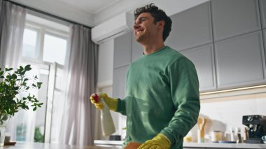 Temizlikçi adam evi yakından silkeliyor. Mutfak tezgahını cilalayan yakışıklı adam. Koruyucu eldivenli gülümseyen çocuk sprey temizleme masasını evde tutuyor. Ev içi rutin kavram