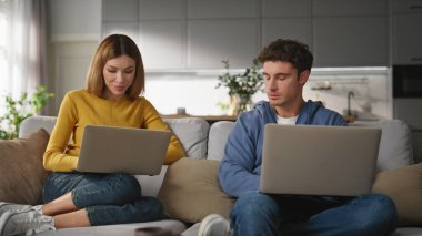 Koltuk kapanışında çalışan bir çift bilgisayar. Ciddi adam sakin kadın klavyeye konsantre oluyor. Genç çiftler, açık oturma odasında birlikte proje çözüyorlar.