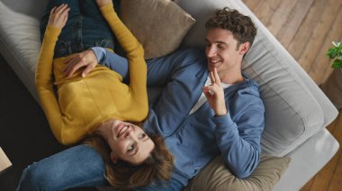 Mutlu çiftler hafta sonları evdeki kanepe kapanışında sohbet ediyorlar. Gülümseyen adam rahat karısını kucaklıyor rahat kanepe manzarasında. Geleceğin içeride yeni bir daireyi tartışacağını hayal eden ilham verici aşıklar.