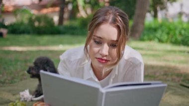 Kapalı kapılar ardında kitap okuyan güzel köpekle piknikte dinlenen kadın. Huzurlu ve entellektüel bir hobiyle güneşli doğaya dalmış rahat bir bayan. Güzel kız siyah kanişlerle battaniyeye uzanmış romandan zevk alıyor.