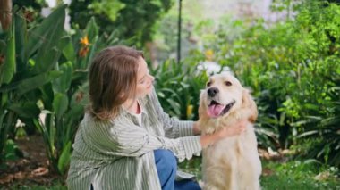Yeşil Park 'ta evcil köpeğini seven neşeli bir kadın. Golden Retriever 'ın açık havada gülümseyen bayan sahibinden sevgi dolu dokunuşları. Yeşillik doğasında, sadık bir dostla esmer bir bağ..