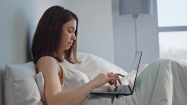 Sabah kızı yatağında dizüstü bilgisayar uygulamasına göz atıyor ve hafta sonunun keyfini çıkarıyor. Rahat iş kadını, bilgisayardaki e-postayı okuyor ve beyaz rahat bir yatakta yatıyor. Huzurlu yatak odasında mutlu serbest çalışmalar.