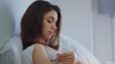 Beyaz, modern yatak odasında ateşini ölçen ciddi bir esmer. Yatakta sıcaklığını ölçen sağlıksız bir kadın hayal kırıklığına uğramış görünüyor. Kız sabahları sağlığını gözlemekten rahatsız..