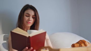 Sabah kızı kitap okuyor, yatakta kahvaltı yapıyor. Kitaplara dalmış, rahat bir yatakta aromatik kahve içen mutlu bir kadın. Sakin esmer, sakin edebiyat hobisinin keyfini çıkarıyor..