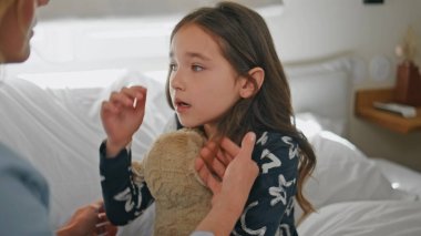 Bilinmeyen bir anne, kızını sakinleştiriyor. Beyaz yatakta saçına dokunuyor. Elinde oyuncak olan üzgün küçük bir kız yatak odasında sorunlar yaşıyor. Tatlı çocuk sabah ağlarken kendini üzgün hissediyor. Annelik kavramı