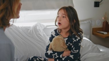 Küçük bir çocuk, beyaz yatak odasında annesine sorun çıkarmayı düşünüyor. Üzgün küçük kız, şefkatli ebeveyniyle konuşan oyuncak ayıyı kucaklıyor. Kızının yatak odasında annesine haber vermesine üzülmüş. Çocukluk kavramı