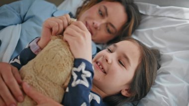 Küçük kız, annesiyle yatak odasında oyuncakçılık oynuyor. Güzel bir bayan tatlı bir çocukla sabah rahatlığının ve huzurunun tadını çıkarır. Huzurlu anne hafta sonu kızıyla rahat bir yatakta uzanıyor.