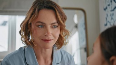 Yakından güzel bir anne, kızı rahat bir evde dinliyor. Modern yatak odasında küçük bir çocukla konuşan pozitif bir kadın. Pijamalı, şefkatli bir kadın. Kimliği belirsiz bir kızla konuşuyor. Hafta sonunun tadını çıkarıyor.