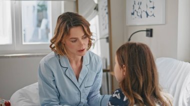 Şefkatli bir anne, sakin bir kız çocuğu, beyaz, yumuşak bir yatakta konuşuyor. Modern yatak odasında sorunlar yaşayan üzgün küçük bir kız. Tatlı çocuk, sabahları annemle konuşurken kendini üzgün hissediyor. Annelik kavramı