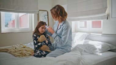 Annesi evde sıcaktan hasta olan kızını ölçüyor. Annesini önemseyen küçük kız yatak odasında oturuyor. Evde elinde dijital termometre cihazı tutan oyuncak ayıyı kucaklayan hasta çocuk. Aile kavramı