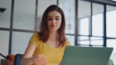 Ofiste dizüstü bilgisayarı uzaktan kontrol eden biri. Gülümseyen iş kadını modern işyerinde oturan belgelere bakıyor. Profesyonel serbest çalışan kağıtları inceleyen, online projeden memnun hisseden.