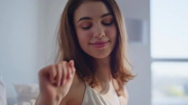 Tasasız kız evde uyanıyor esneme hareketleri yapıyor ve rahatlamış hissediyor. Yatakta akıllı telefona benzeyen neşeli genç bir kadın sakin bir hafta sonu sabahının tadını çıkarıyor. Gülümseyen esmer, sakin yatak odasında cep telefonuna bakıyor..