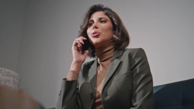 Ofis lobisinde cep telefonuyla konuşan gülümseyen bir iş kadını. Güzel bayan iş yöneticisi iş yerinde önemli bir telefon görüşmesi yapıyor. Şirket ortamında telefonda profesyonel tartışma anlaşması..