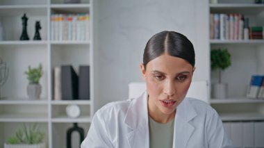 Sağlık danışmanı ofis kliniğinde çevrimiçi iletişim kuruyor. Modern teknolojiyle telekonksiyon hizmeti veren profesyonel bir kadın. Tıbbi giysili kadın doktor uzaktan tavsiye veriyor..