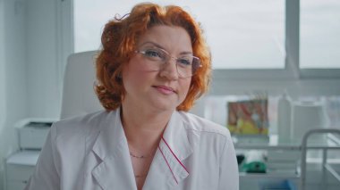 Sağlık hizmetleri konsültasyonundaki özenli sağlık görevlisi hasta, yakın çekim. Tıp kliniğinde kızıl saçlı profesyonel bir sağlık sigortası randevusu var. Kadın doktor, sağlık sorunları olan poliklinik ziyaretçilerini değerlendiriyor..