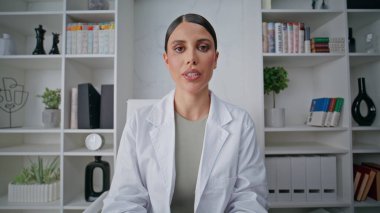 Klinikteki pov video çekiminde web kamerasıyla teletıp danışmanlığı yapan doktor. Uzman kadın sağlık bilgilerini uzaktan açıklıyor. Beyaz önlüklü doktor laptoptan danışmanlık yapıyor..