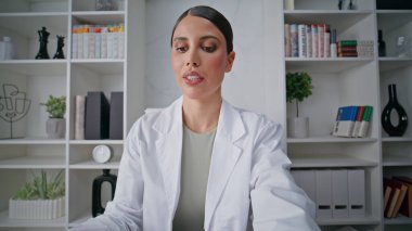 TeleHealth uzmanı klinikteki pov videosundaki bilgisayar kamerasıyla konuşuyor. Uzman bir kadın tıbbi tavsiyelerde bulunuyor. Sağlık merkezinde internet sohbeti yapan yetenekli bir hekim.