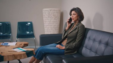 Modern ofis ortamında cep telefonuyla iletişim kuran güzel bir kız. Kanepede oturan ciddi profesyonel yönetici akıllı telefon konuşmalarıyla meşgul. Şık bir iş kadını koltuktan cep telefonunu arıyor..