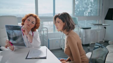 Dinleyen bir doktor klinik muayenesinde röntgeni açıklıyor. Sağlık hizmetleri ziyaretinde tıbbi danışmanlık yapan pratisyen hekim. Profesyonel radyologlar ofiste bayan hastalarla konuşuyor..