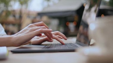 Dışarıdaki kafede dizüstü bilgisayar kullanan bir kadın. Klavye kablosuz bilgisayarı üzerinde çalışan profesyonel parmaklar işle meşgul. Sokak kafeteryasında e-posta yazan tanınmamış kadın serbest yazar..