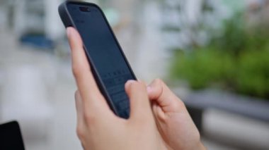 Dışarıdaki akıllı telefondan mesaj atan kadın elleri kapalı. Şehir sokağındaki cep telefonu ekranında mesaj yazan kimliği belirsiz genç bir bayan. Tanımlanamayan iş kadını dışarıda cep telefonunda gezinme uygulaması.