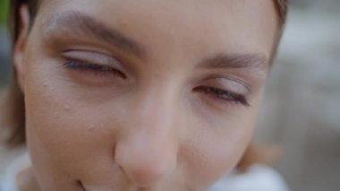 Yakından güzel kadın gözleri sakin bir ifadeyle kameraya bakıyor. Çekici yeşil gözlü kızın portresi açık havada gülümseyerek poz veriyor. Şirin genç bayan sokakta yalnız başına dinleniyor. Doğal güzellik.