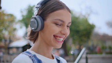 Neşeli zoomer. Kulaklıkla müzik dinliyor. Neşeli bir şekilde kapanış yapıyor. Mutlu kadın gülerek güneşli şehir parkında en sevdiği şarkıyı söylüyor. Kulaklıklı rahat kız melodisi açık havada dinleniyor..